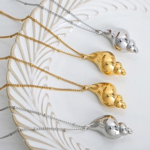 Elegant conch shell pendant necklaces in polished gold and silver on a white tray