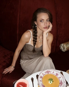 Detail of a brown woven texture corset vest paired with elegant pearl jewelry and accessories
