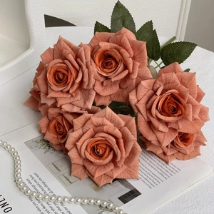 Close-up of realistic orange artificial silk roses with pearl necklace on a magazine