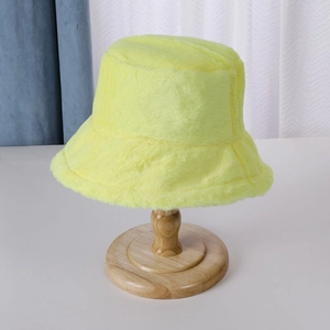Detail of yellow faux fur bucket hat material texture on a wooden stand