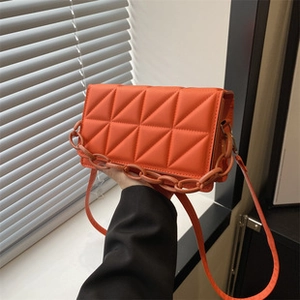 Detail of orange quilted PU leather tote bag with thick chain handle and shoulder strap