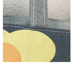 Detail view of reinforced stitching on grey canvas tote bag with abstract floral print