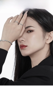 Close-up of a model wearing frosted texture silver rings and a wavy bangle