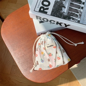 Close-up of floral drawstring storage pouch with bear patterns on a rustic wooden seat