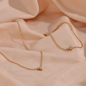 Detailed shot of 18K gold plated jewelry set with lotus zircon charms on silk