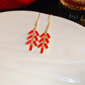 Detail of red firecracker drop earrings with golden hooks and enamel finish