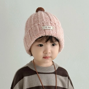 Detail der rosa gestrickten Wintermütze mit braunem Bommel und Markenlogo für Kinder