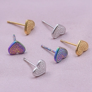 Detailed macro view of heart-shaped earrings with textured grain finish in three colors