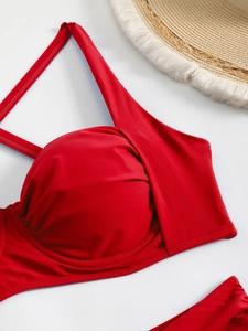Detail of red bikini top with pleated cups and summer straw hat on white background