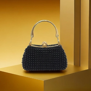 Detail of black beaded evening clutch featuring a gold metal handle and crystal accents