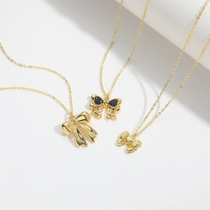 Detailed view of three minimalist gold bow pendant necklaces with black gemstone accents