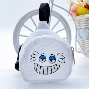Close-up of a mini white canvas backpack keychain with a cute embroidered cartoon face