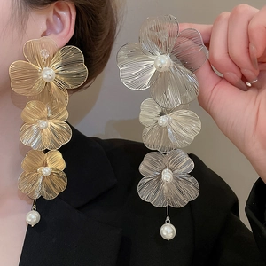 Dettaglio di grandi orecchini a fiore in oro e argento con perle bianche rotonde