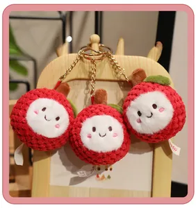 Detailed view of three red lychee plush pendants with cute faces on a wooden display