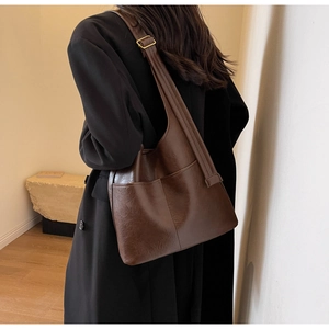 Braune Leder-Beuteltasche getragen vom Model, zeigt das große Fassungsvermögen und Design