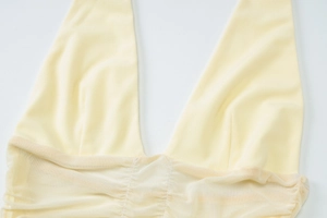 Detail of the plunging V-neckline and sheer mesh ruching on this pale yellow dress