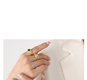 Detail of twisted gold rings set with green and white oval cubic zirconia stones