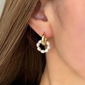 Détail d'une boucle d'oreille en or 18K avec un pendentif amovible en perles blanches