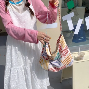 Detail of large capacity canvas shoulder bag with colorful stripes and woven texture strap