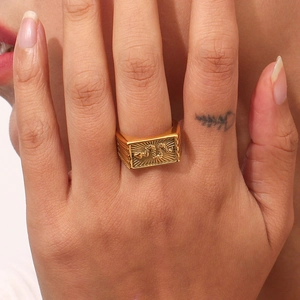 Detail of 18K gold plated square signet ring featuring embossed snake and sunburst motif