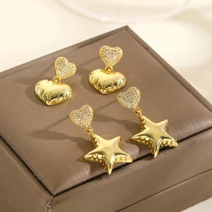 Golden heart and star dangle earrings set with sparkling cubic zirconia on brown leather