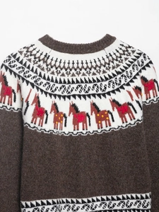Detailed close-up of brown Fair Isle knit sweater featuring decorative horse patterns