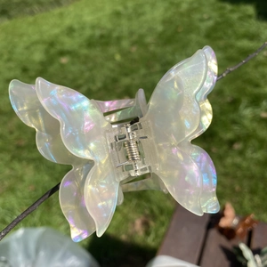 Macro view of a colorful iridescent butterfly hair claw clip under natural outdoor sunlight