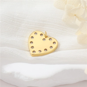 Close-up of a gold heart pendant with sparkling round stones on white textured fabric