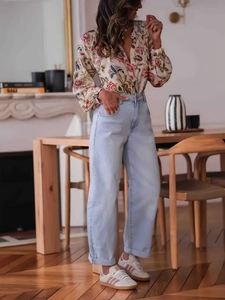 Woman in floral long sleeve blouse and high waist jeans in a warm home setting