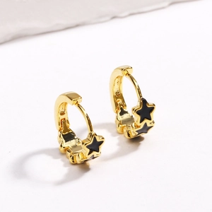 Close-up of golden hoop earrings featuring black star charms on a white background