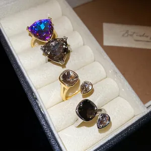 Elegant geometric gold rings set with large triangle and square crystals in a jewelry box