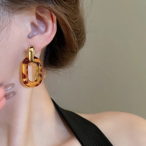 Detail view of leopard print resin earrings with golden chain links worn by model