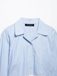 Détail d'une chemise à rayures bleu clair avec col classique et bordure en dentelle blanche