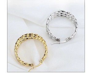 Macro shot of large gold and silver twisted hoop earrings on white textured fabric
