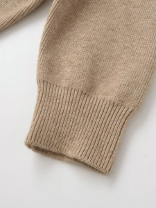 Detail shot of khaki knitted sweater cuff showing soft texture and fine fabric weave