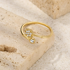 Detail of gold open ring with hexagonal flower and round diamond on stone background
