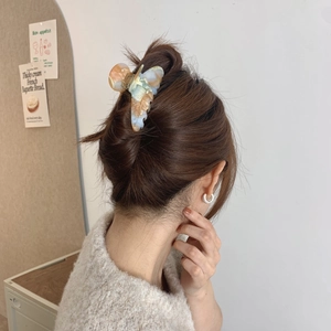 Close-up of a marbled acetate claw clip securing a bun on wavy dark brown hair