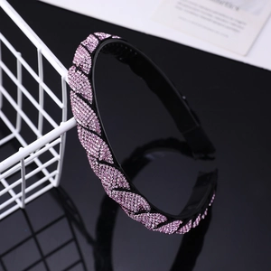 Detail view of pink rhinestone headband with non-slip teeth on black reflective surface