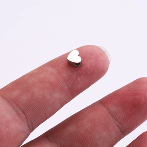 Polished silver stainless steel heart bead held in hand to show size and mirror finish