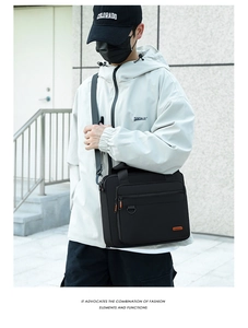 Close-up of black commuter crossbody bag with front zipper pocket on model with trench coat