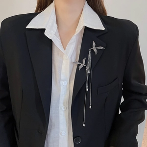 Detail of silver phoenix brooch with pearl tassels on black blazer for elegant style