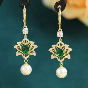 Detailed macro of vintage lotus earrings with green gemstone and hanging pearl