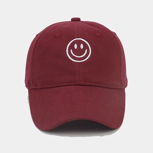 Close-up of white smiley face embroidery on a burgundy cotton baseball cap