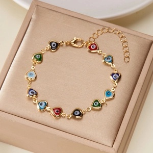 Detailed view of heart-shaped evil eye links on a gold bracelet over a jewelry box