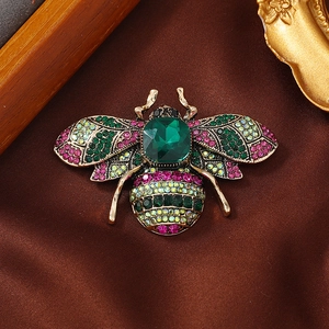 Exquise broche abeille en cristal avec des strass colorés et une pierre centrale verte.
