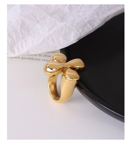 Artistic gold flower ring with thick fluid design displayed on elegant dark plate