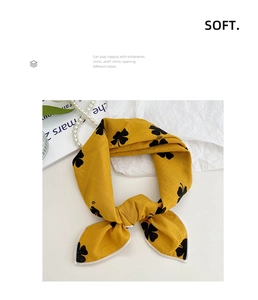 Close-up of ginger yellow floral cotton linen scarf tied as a bow with clover print