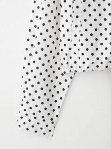 Vue détaillée d'une veste à pois noirs et blancs avec ourlet élastique et finitions soignées