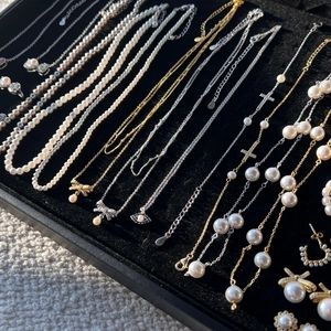 Close-up of S925 silver jewelry set featuring pearl necklaces and bow pendants on velvet