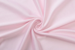 Macro shot of pink layered tiered dress fabric with soft woven texture and spiral folds